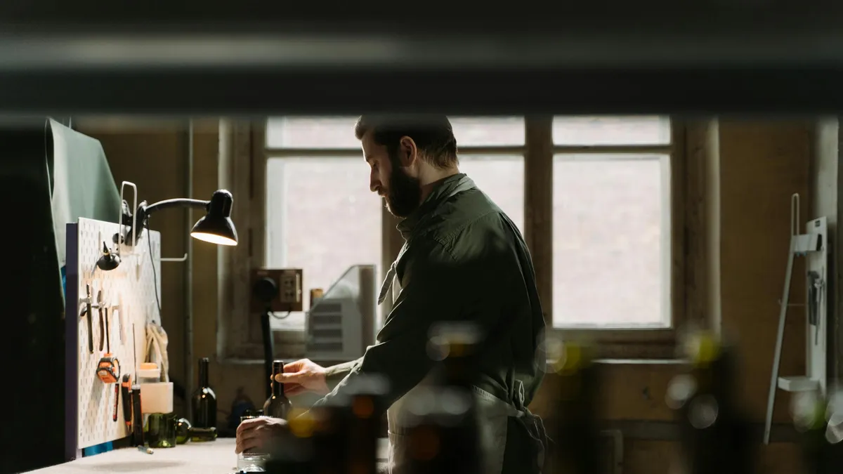 Artisan au travail dans son atelier, entouré de ses outils sous une lumière chaleureuse