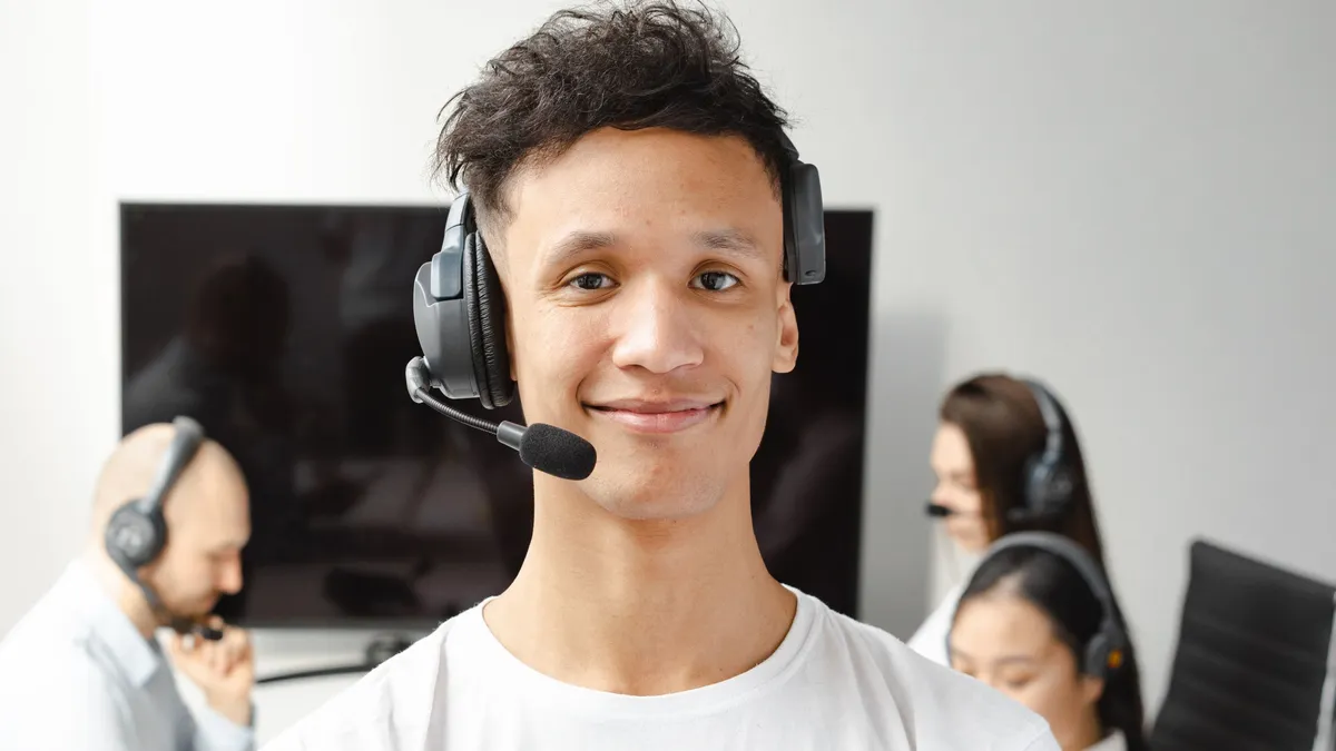 Conseiller en relation client souriant, équipé d'un casque, dans un bureau moderne