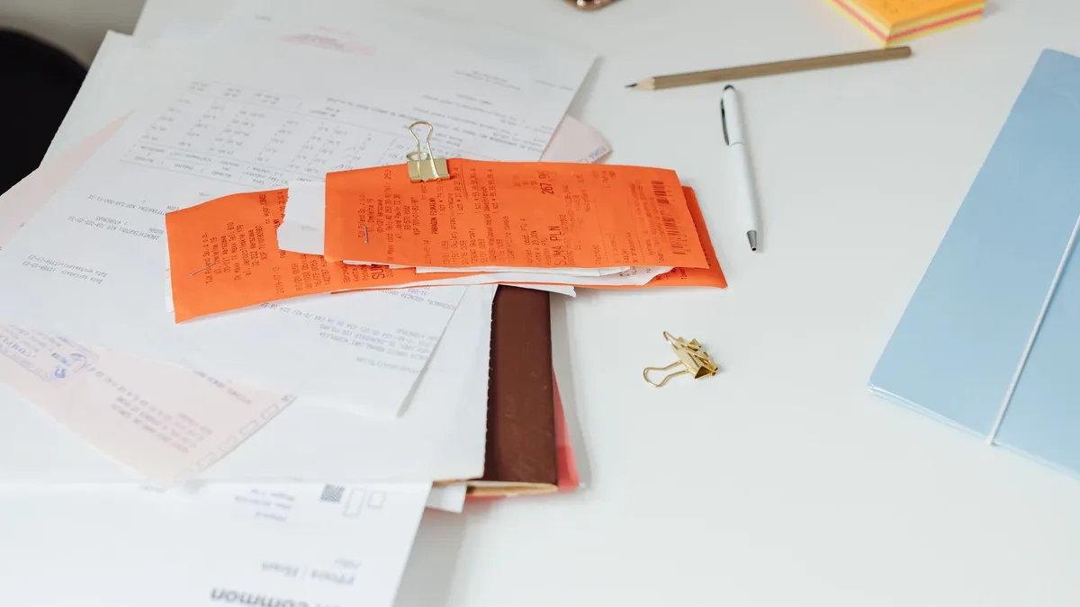 Bureau ordonné avec reçus, documents et fournitures, illustrant la gestion administrative manuelle
