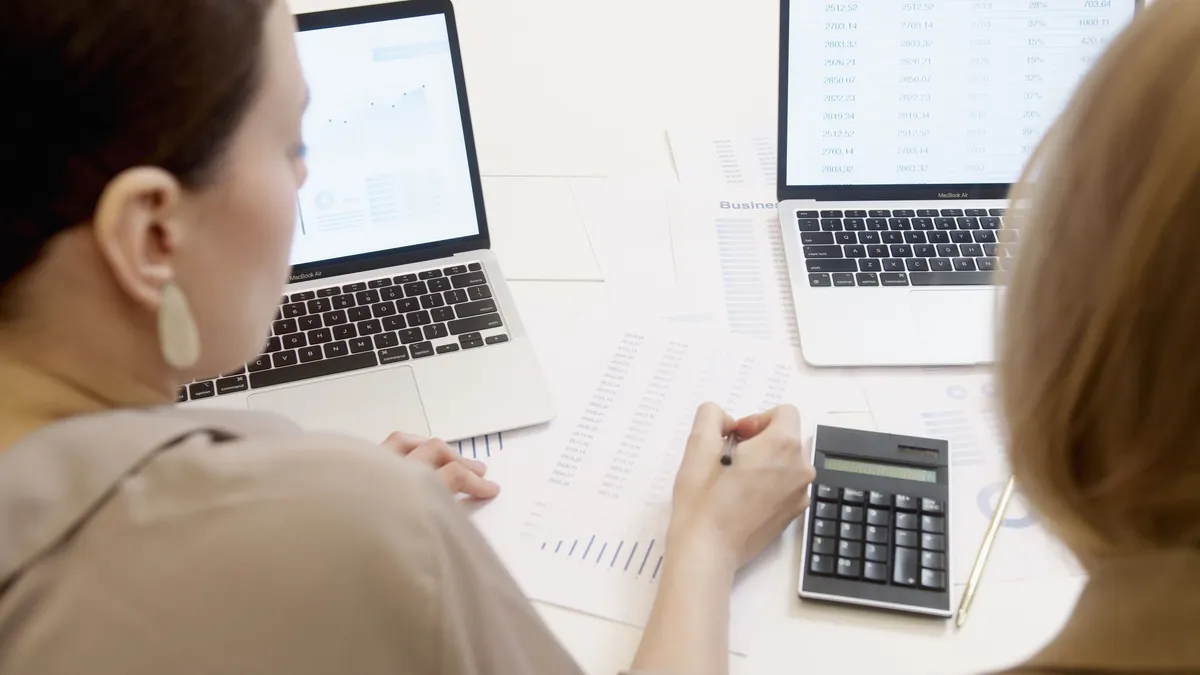 Deux personnes analysant des données d'entreprise sur des ordinateurs portables avec graphiques